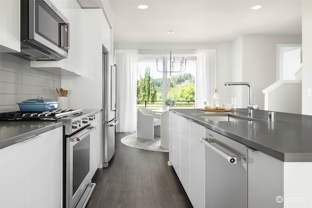 kitchen with sink, pendant lighting, white cabinets, and premium appliances