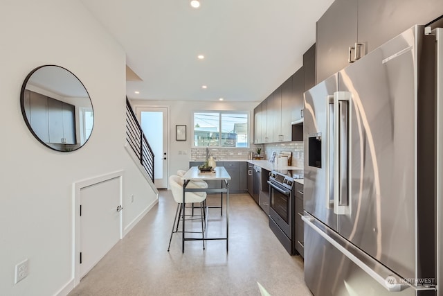 kitchen with a kitchen breakfast bar, decorative backsplash, and stainless steel appliances