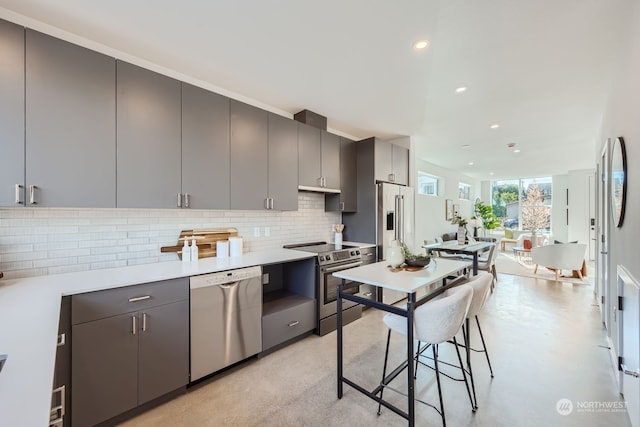 kitchen with gray cabinetry, stainless steel appliances, and tasteful backsplash