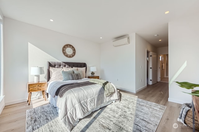 bedroom featuring a wall unit AC and light hardwood / wood-style floors