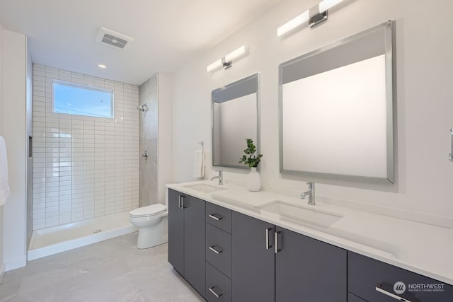 bathroom with vanity, toilet, and tiled shower