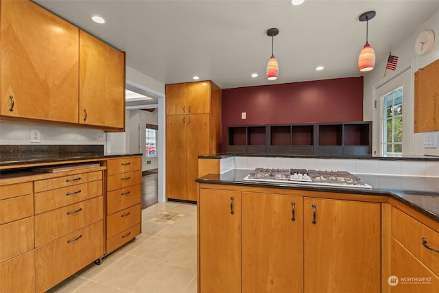 kitchen with stainless steel gas stovetop, light tile patterned flooring, and decorative light fixtures