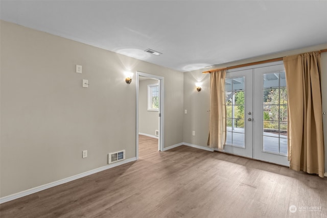 spare room featuring french doors and light hardwood / wood-style flooring