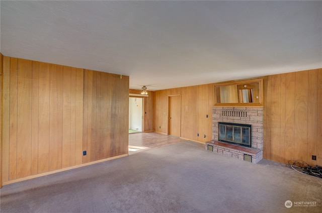 unfurnished living room with a fireplace, light carpet, and wooden walls