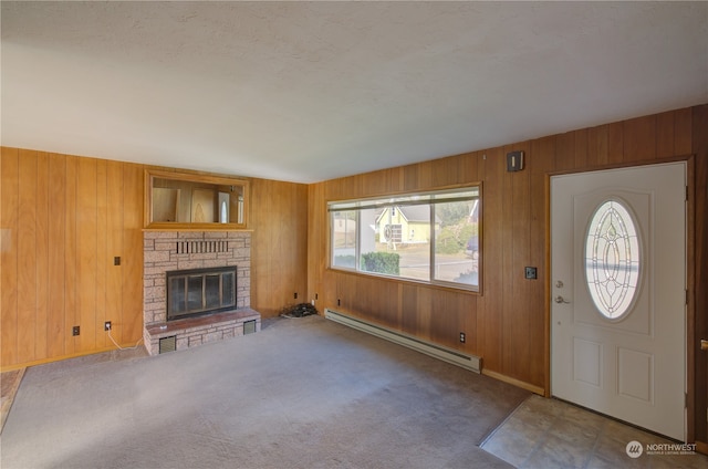 carpeted foyer with baseboard heating, wood walls, and a fireplace