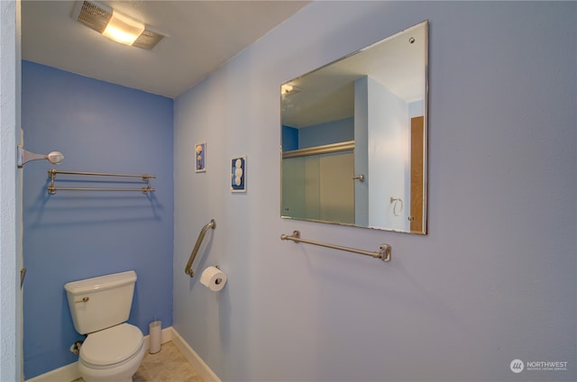 bathroom featuring tile patterned flooring, toilet, and walk in shower