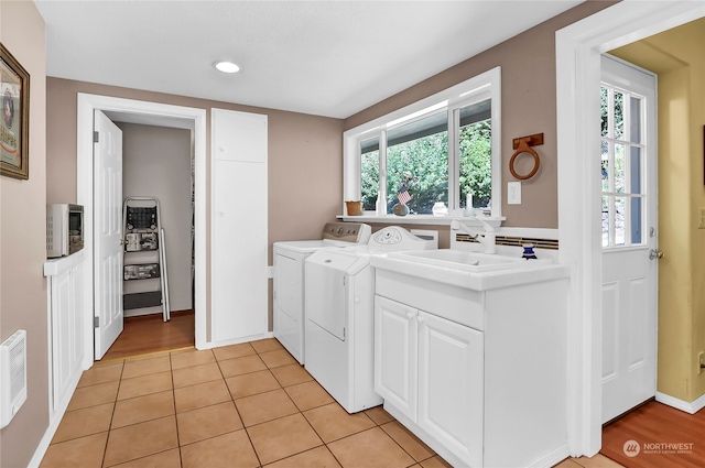 laundry room with washer and dryer, sink, light hardwood / wood-style flooring, and cabinets