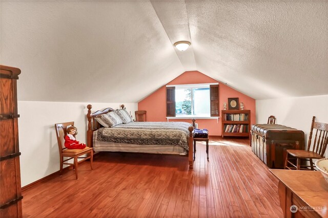 bedroom featuring a textured ceiling, vaulted ceiling, and hardwood / wood-style flooring