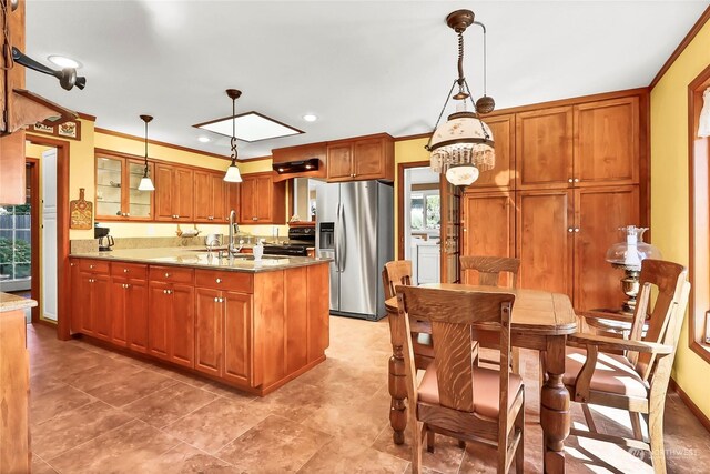 kitchen with hanging light fixtures, stainless steel fridge, ornamental molding, and light stone counters