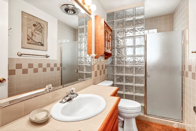 bathroom with walk in shower, tile walls, vanity, and toilet