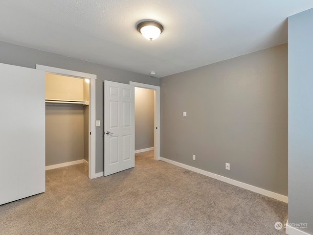 unfurnished bedroom featuring a spacious closet, light carpet, and a closet