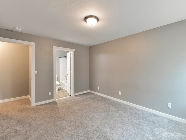 unfurnished bedroom featuring connected bathroom and light colored carpet