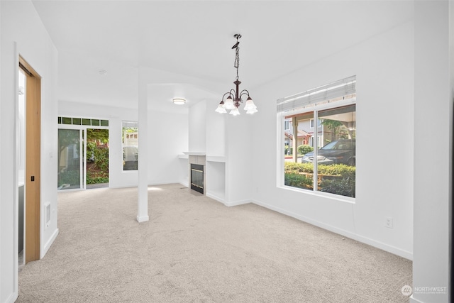 unfurnished living room with light carpet and a chandelier