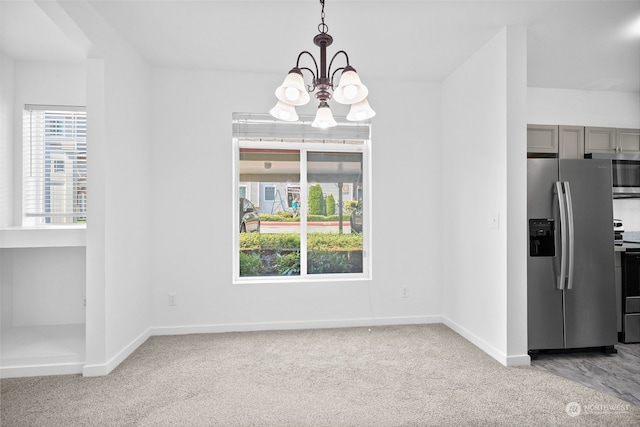 unfurnished dining area with carpet floors and a notable chandelier