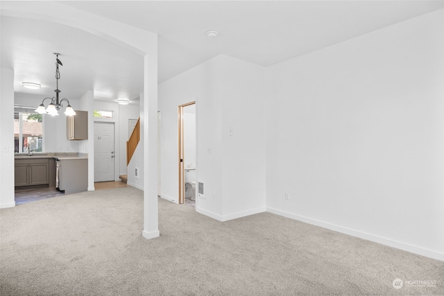 unfurnished living room featuring light carpet, an inviting chandelier, and sink