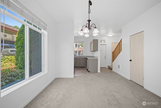 unfurnished dining area with a chandelier and light colored carpet