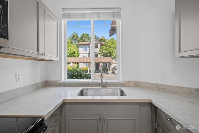 kitchen with range, sink, gray cabinets, and light stone counters