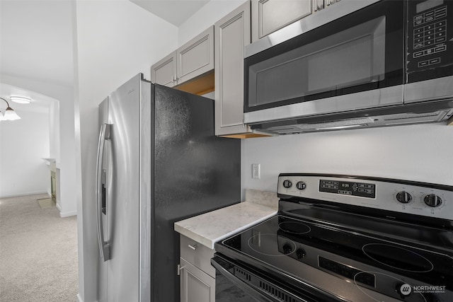 kitchen with gray cabinets, stainless steel appliances, and carpet