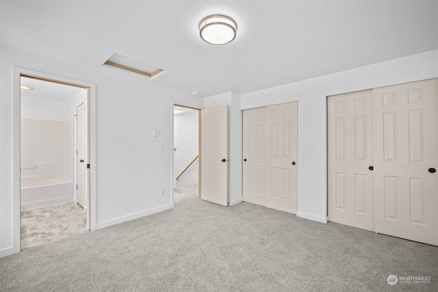 unfurnished bedroom with connected bathroom, two closets, and light carpet