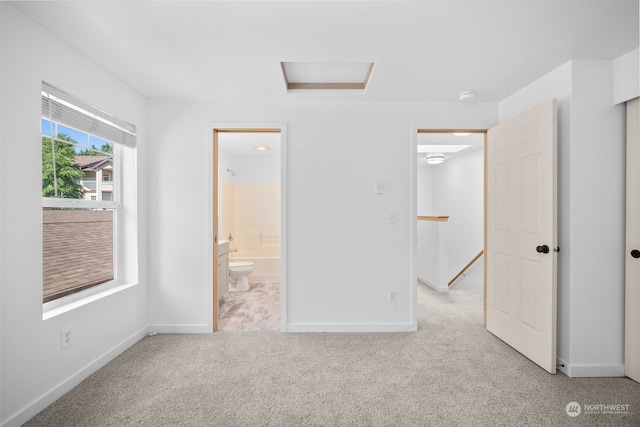 unfurnished bedroom with ensuite bath and light carpet