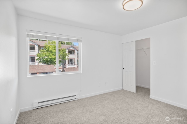 unfurnished bedroom with light carpet, a baseboard heating unit, and a closet