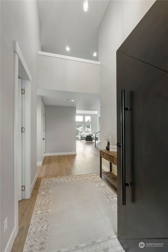 hallway with light wood-type flooring and a high ceiling