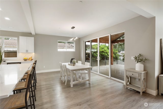 dining space with an inviting chandelier, light hardwood / wood-style floors, and beamed ceiling