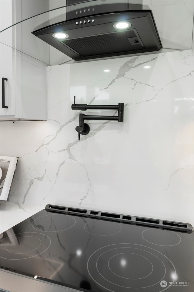 details with white cabinets, stove, decorative backsplash, extractor fan, and light stone countertops