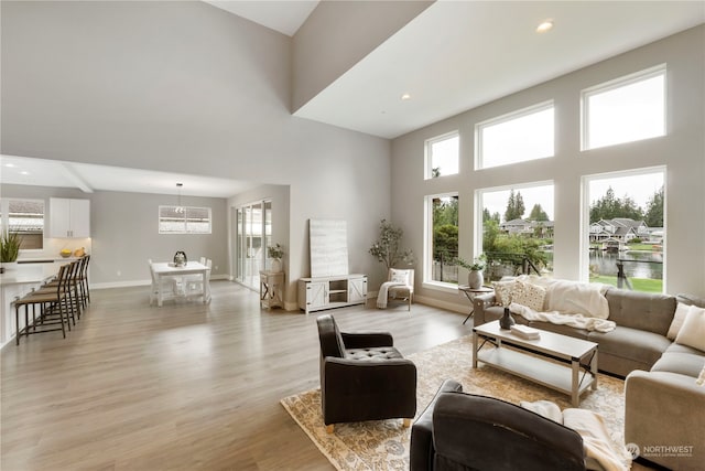 living room with light hardwood / wood-style flooring, a high ceiling, and a water view