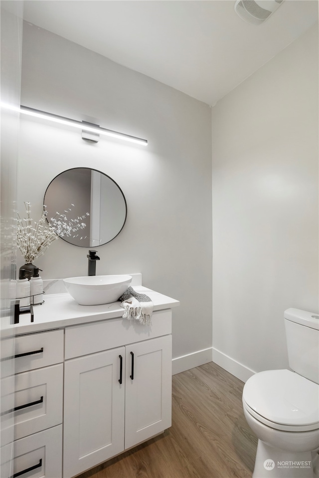 bathroom with wood-type flooring, vanity, and toilet