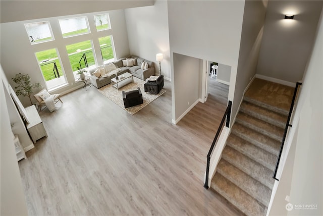 living room featuring light wood-type flooring and a high ceiling