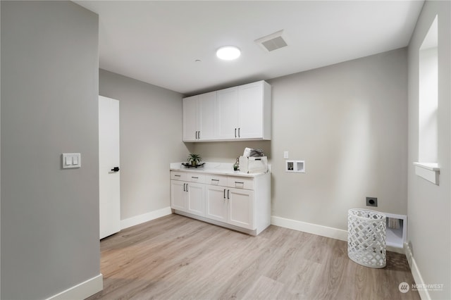 clothes washing area featuring washer hookup, cabinets, light hardwood / wood-style floors, and electric dryer hookup