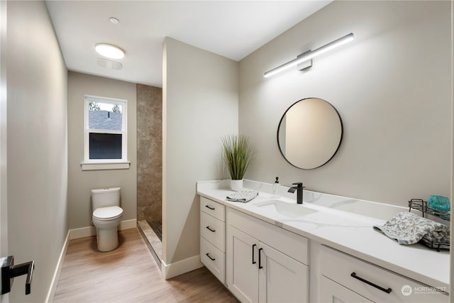 bathroom featuring a shower, vanity, toilet, and hardwood / wood-style flooring