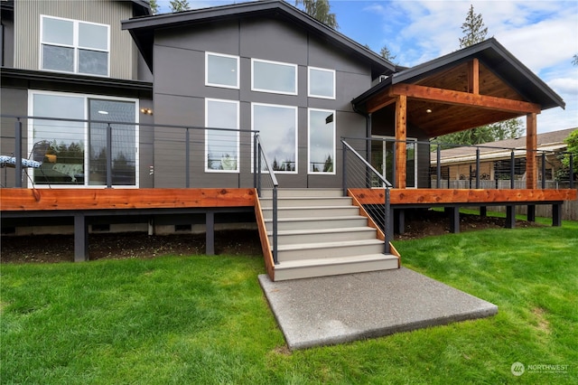 rear view of property featuring a lawn and a deck