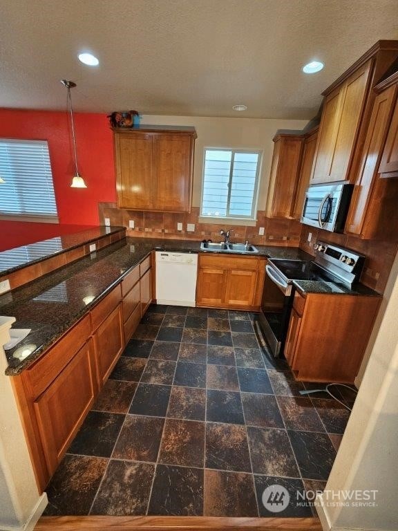 kitchen featuring kitchen peninsula, sink, decorative light fixtures, and appliances with stainless steel finishes