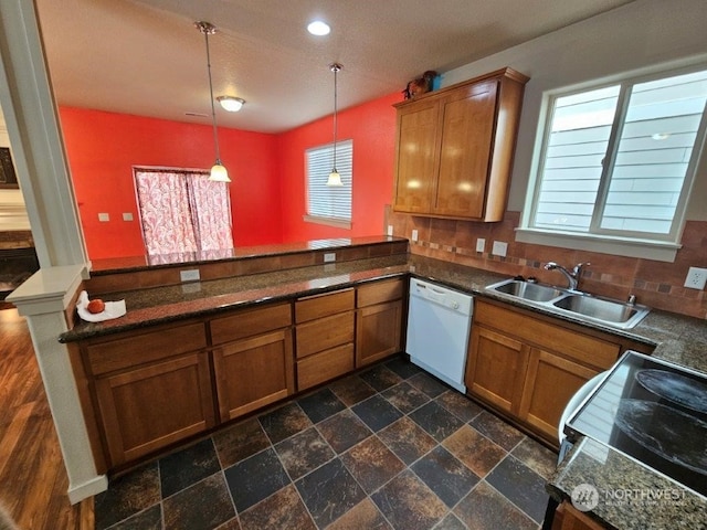 kitchen featuring dishwasher, sink, a wealth of natural light, kitchen peninsula, and pendant lighting