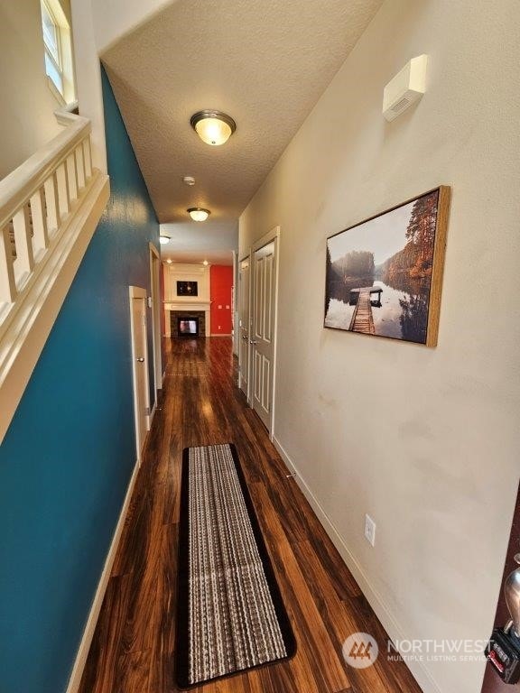 hall with a textured ceiling and dark hardwood / wood-style floors