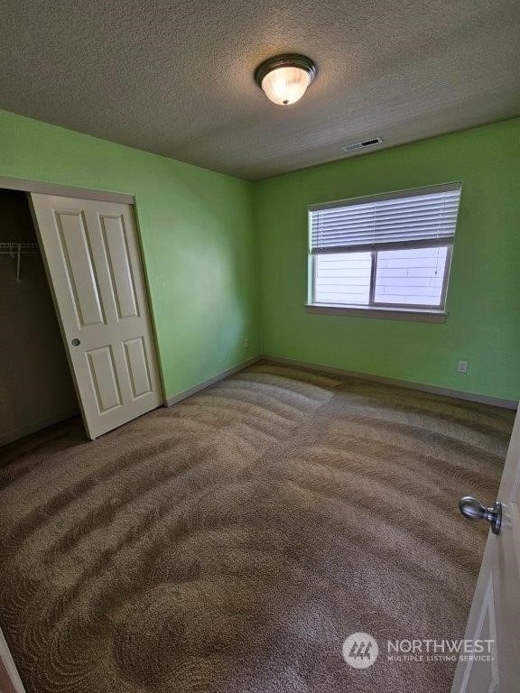 unfurnished bedroom featuring a textured ceiling, a closet, and carpet floors