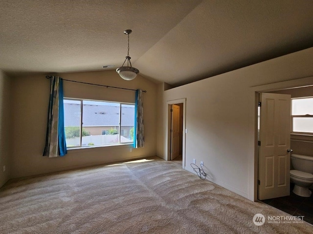 unfurnished room featuring carpet, a textured ceiling, and vaulted ceiling