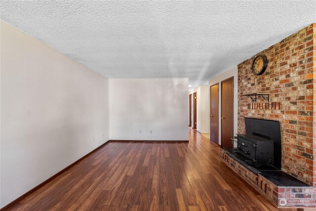 unfurnished living room with a wood stove, dark hardwood / wood-style floors, and a textured ceiling