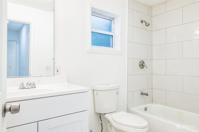 full bathroom featuring tiled shower / bath, vanity, and toilet