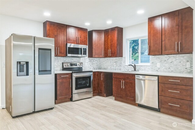 kitchen featuring appliances with stainless steel finishes, backsplash, light hardwood / wood-style floors, and sink