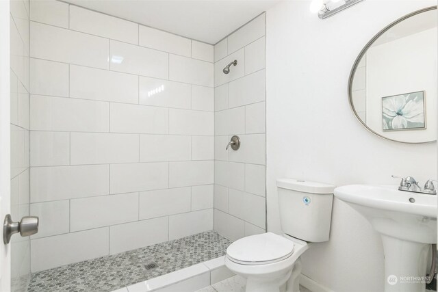 bathroom featuring tiled shower and toilet