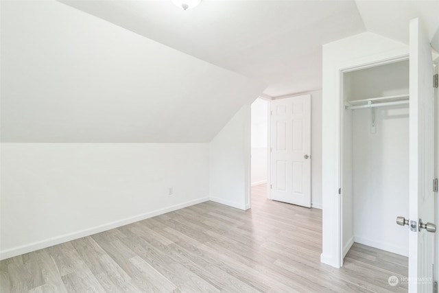 unfurnished bedroom featuring vaulted ceiling, light hardwood / wood-style flooring, and a closet