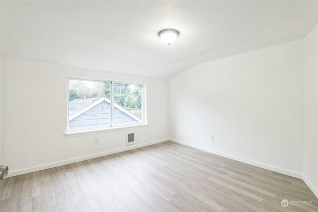 empty room with light hardwood / wood-style flooring and vaulted ceiling