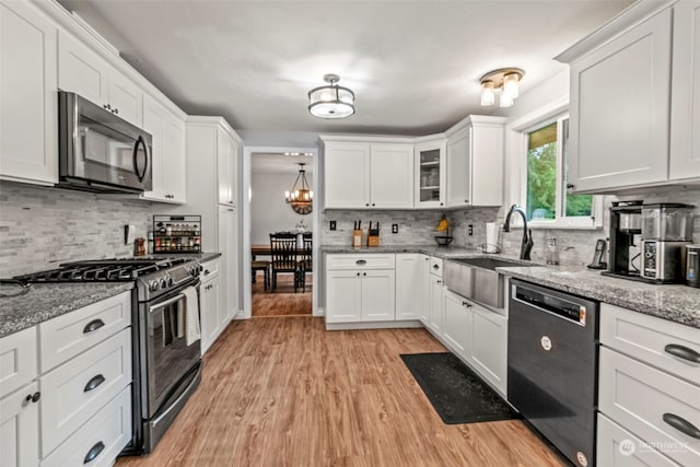 kitchen with white cabinetry, stainless steel appliances, sink, light stone countertops, and light hardwood / wood-style floors