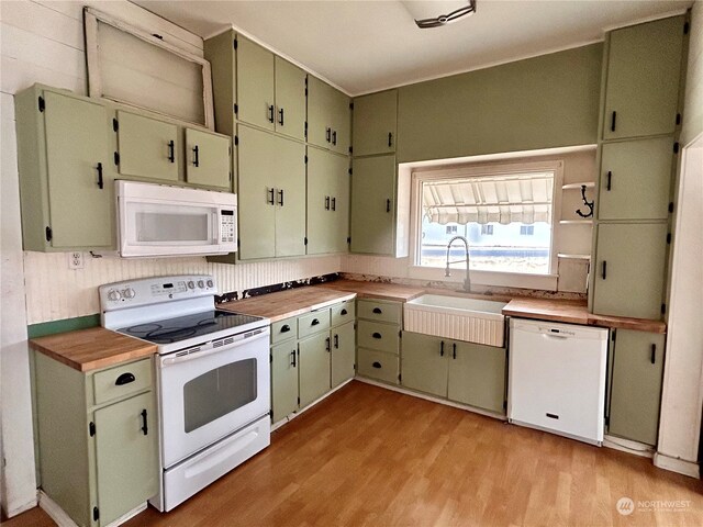 kitchen with white appliances, light hardwood / wood-style flooring, green cabinetry, and sink