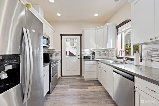 kitchen with stainless steel appliances, white cabinetry, light hardwood / wood-style floors, and sink