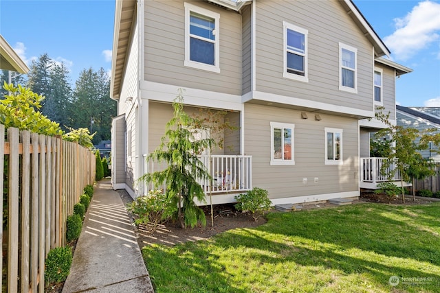 back of property with a lawn and covered porch