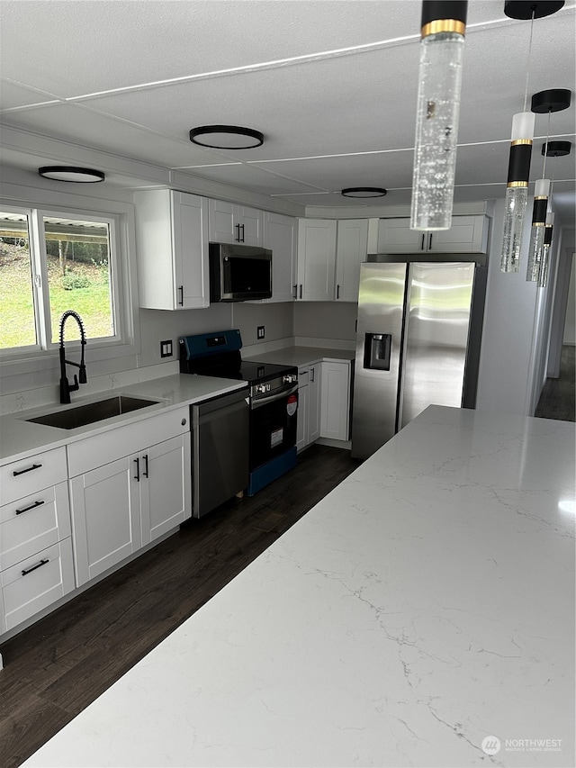 kitchen featuring appliances with stainless steel finishes, white cabinetry, light stone countertops, dark hardwood / wood-style floors, and sink